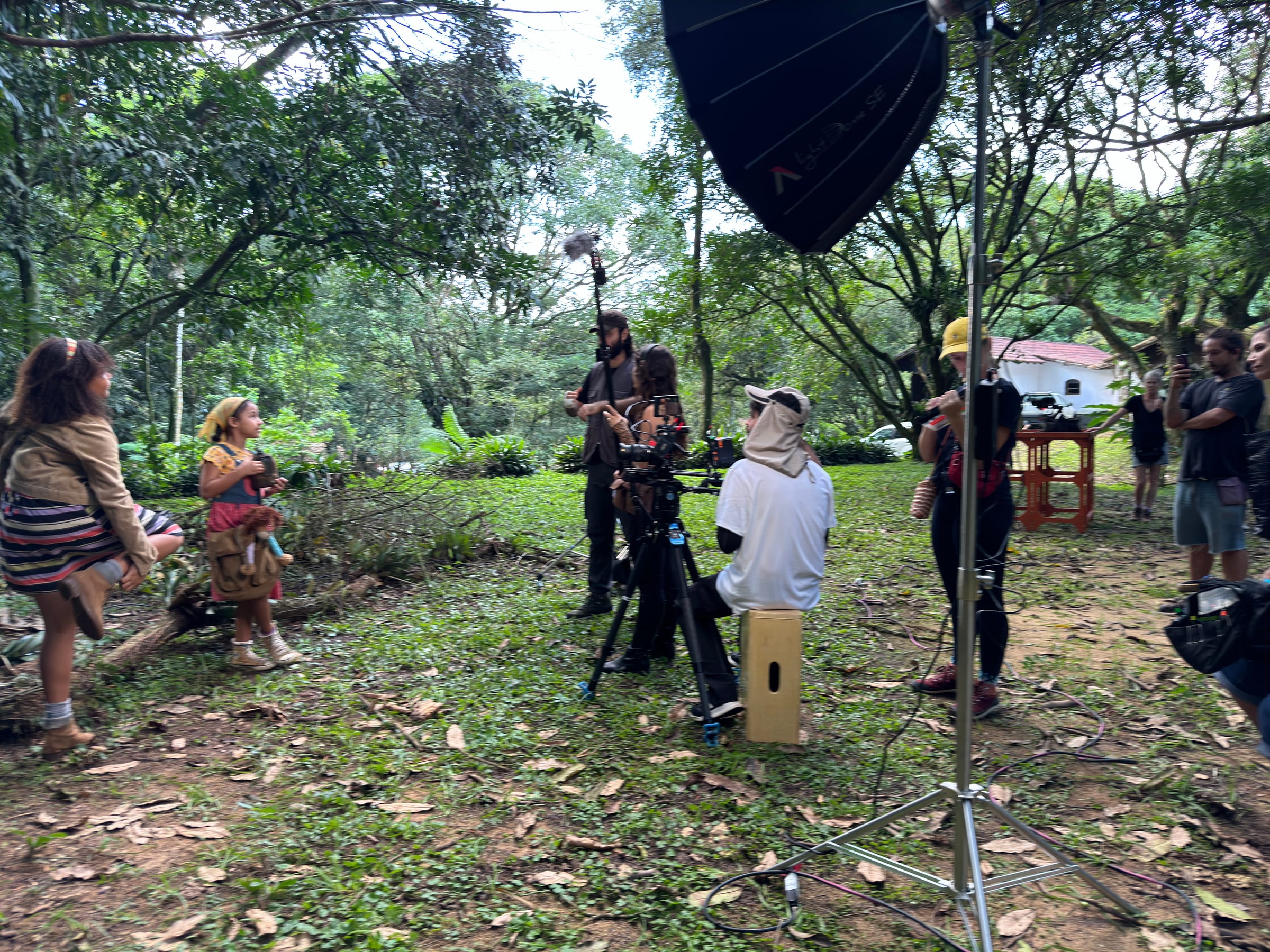 Plano aberto mostra equipe e iluminação em uma locação na mata