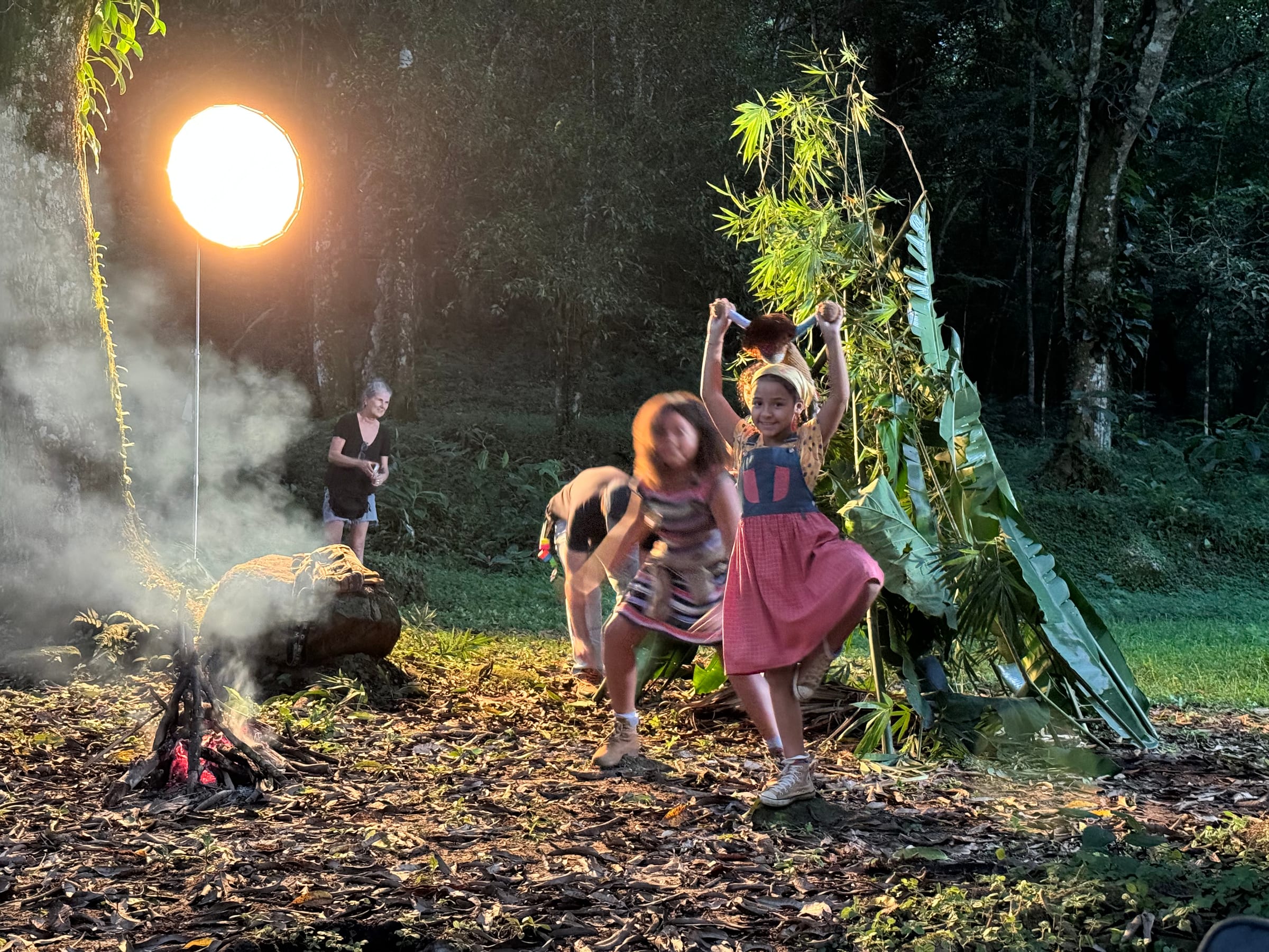 Atrizes contracenam junto ao fogo com a iluminação de set visível