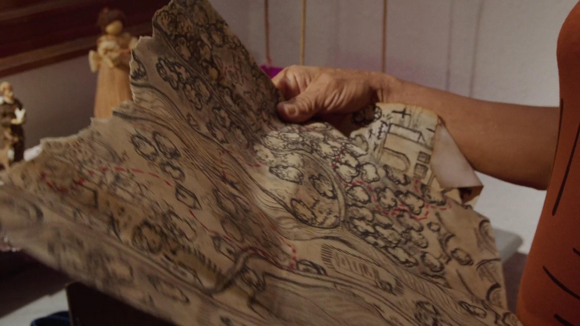 Mãos abrem o mapa desenhado que conduz ao tesouro